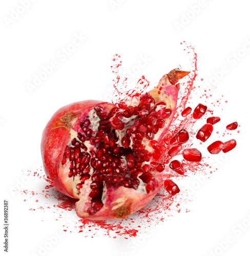 Falling and crack pomegranate with splashes of juice and seeds