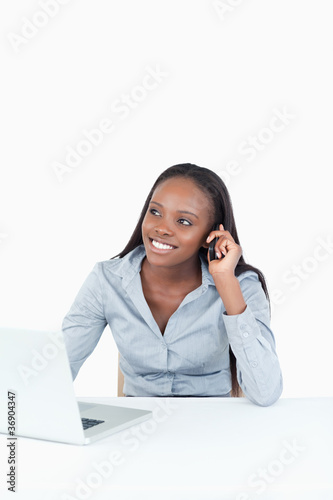 Portrait of a woman making a phone call while using a notebook