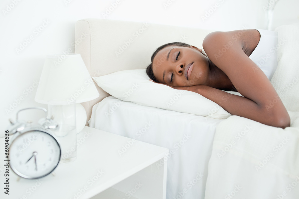 Young woman sleeping while her alarm clock is ringing Young woman sleeping while her alarm clock is ringing