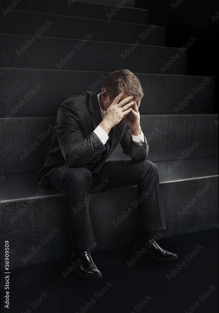 Young businessman sitting on stairs with head down Young businessman sitting on stairs with head down