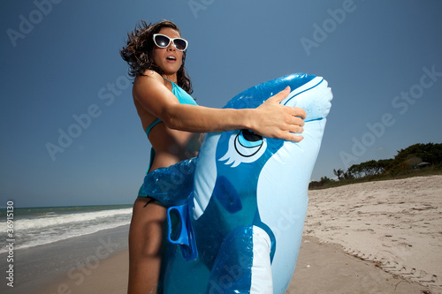 Young Brunette Woman playing with Inflatable whale on the beach