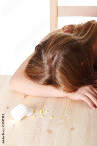 Young woman lying on table full of pills.