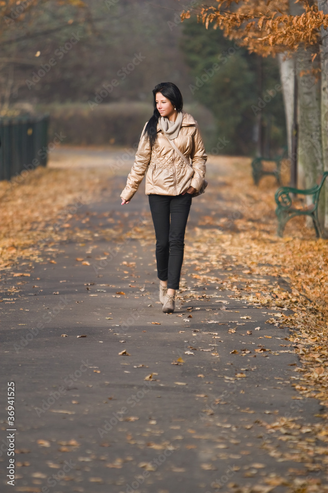 pretty young woman walking in autumn park
