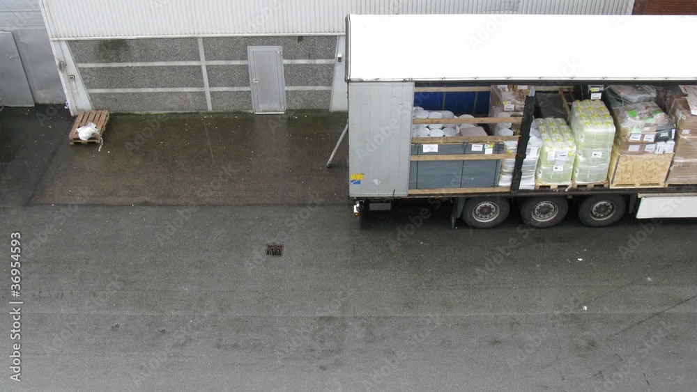 Truck full of goods stationed near warehouse, time lapse