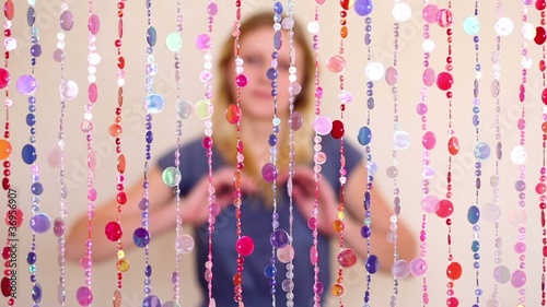 Girl sit behind beads curtain, blurred photo