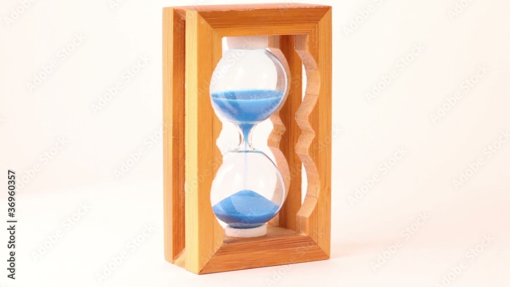 Hand take wooden framed hourglass, turn over and put it back