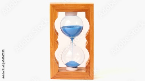 Blue sand pours inside wooden framed hourglass measured time photo