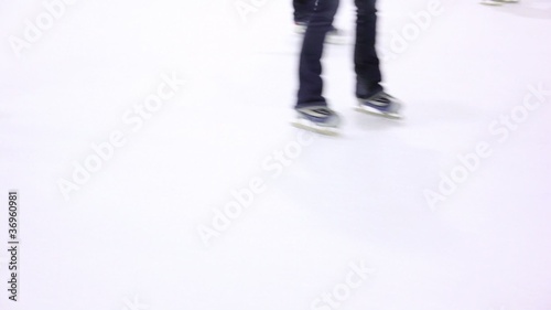 Several people skate on ice rink, only legs are visible photo