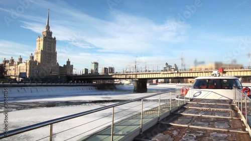 ship moving away from bridge, building of Stalin era in distance photo