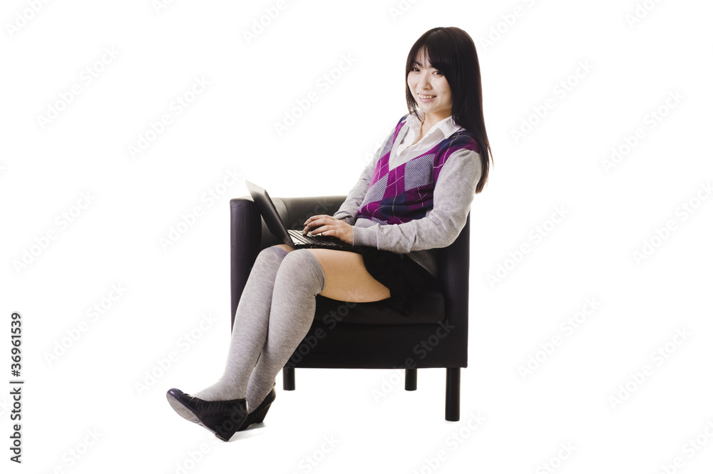 Chinese student working on a laptop and sitting in a chair. Chinese student working on a laptop and sitting in a chair.