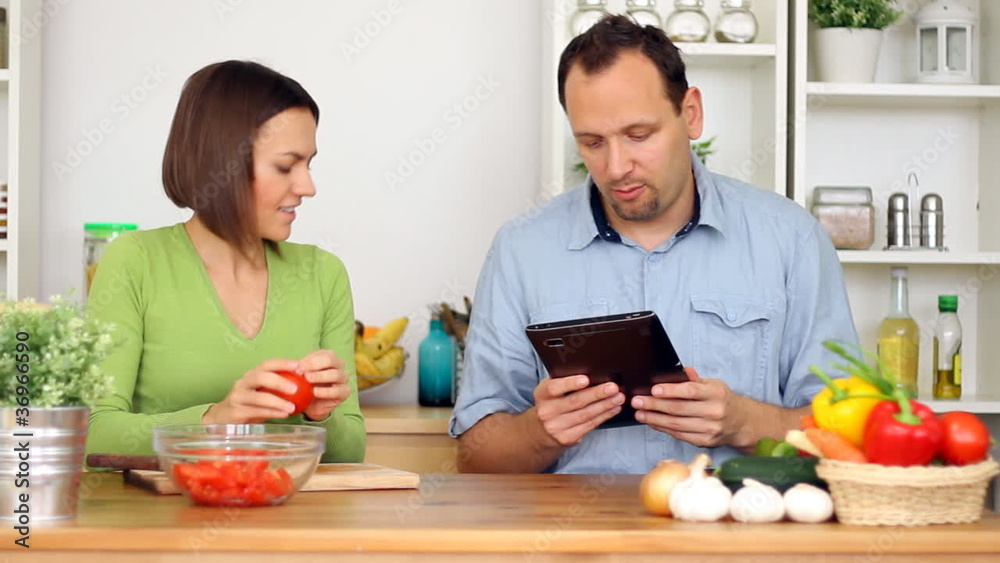 Couple using a tablet computer during cooking Couple using a tablet computer during cooking