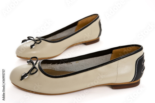Pair of beige female shoes with black bow over white background