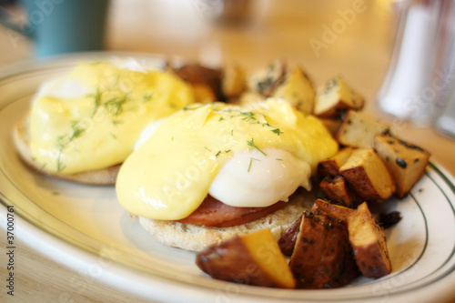 Delicious eggs benedict with seasoned potatoes for breakfast.