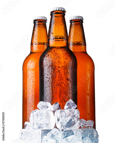 Three brown bottles of beer with ice isolated on white