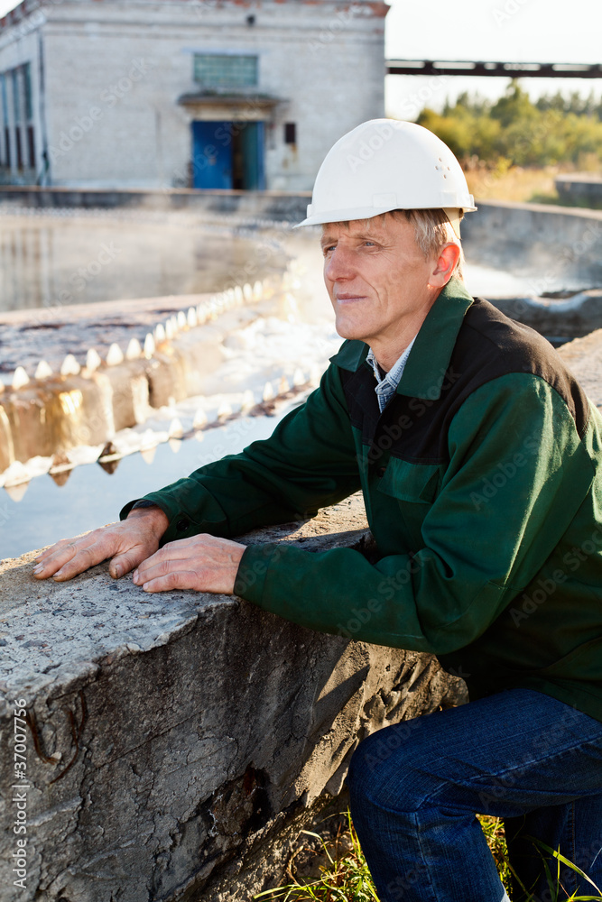 Manual worker in hardhat near water settler in plant Manual worker in hardhat near water settler in plant