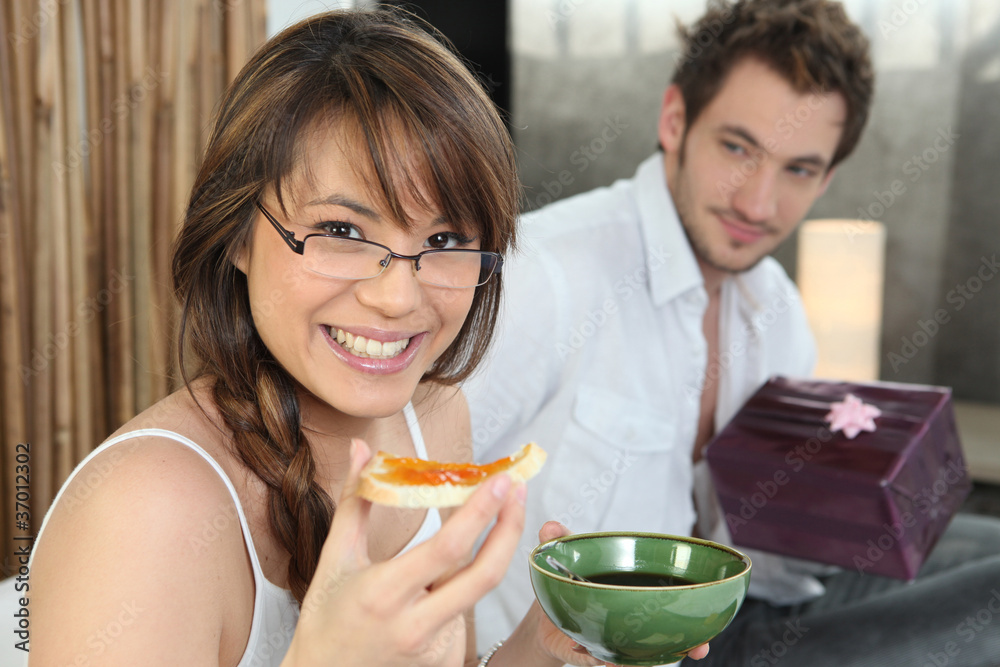 Man offering girlfriend present at breakfast Man offering girlfriend present at breakfast