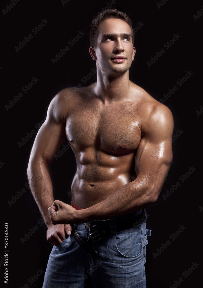 Naklejka premium young muscular man isolated on black background