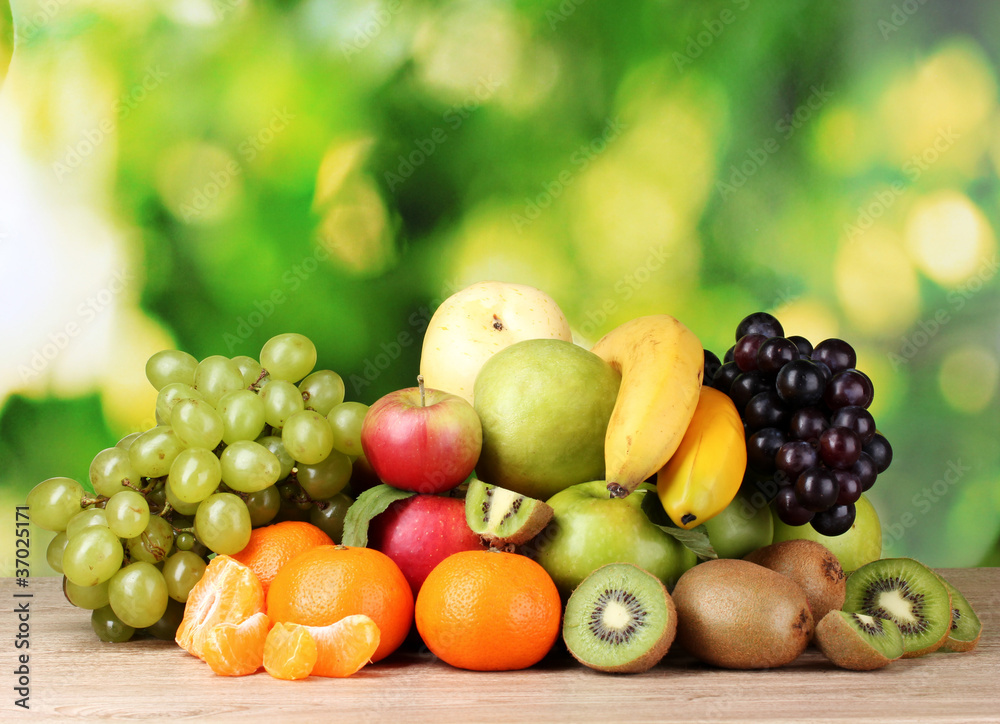 Ripe juicy fruits on wooden table on green background Ripe juicy fruits on wooden table on green background