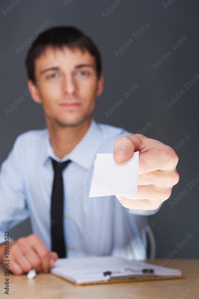 Business man handing a blank business card over grey background Business man handing a blank business card over grey background