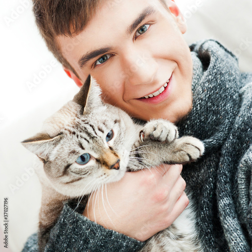 Relaxed man sitting on armchair holding and petting pet cat photo