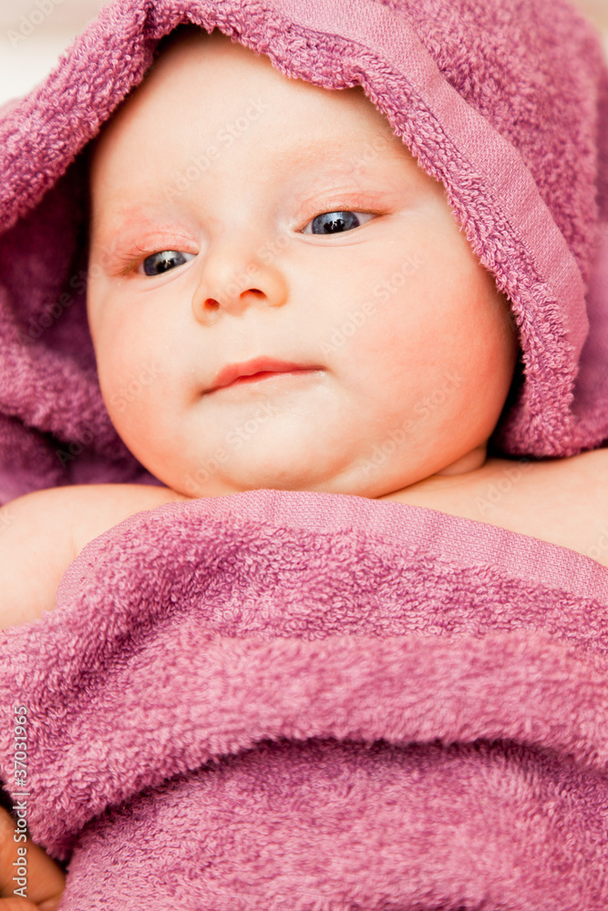 Infant baby girl smiling laying in violet towel Infant baby girl smiling laying in violet towel