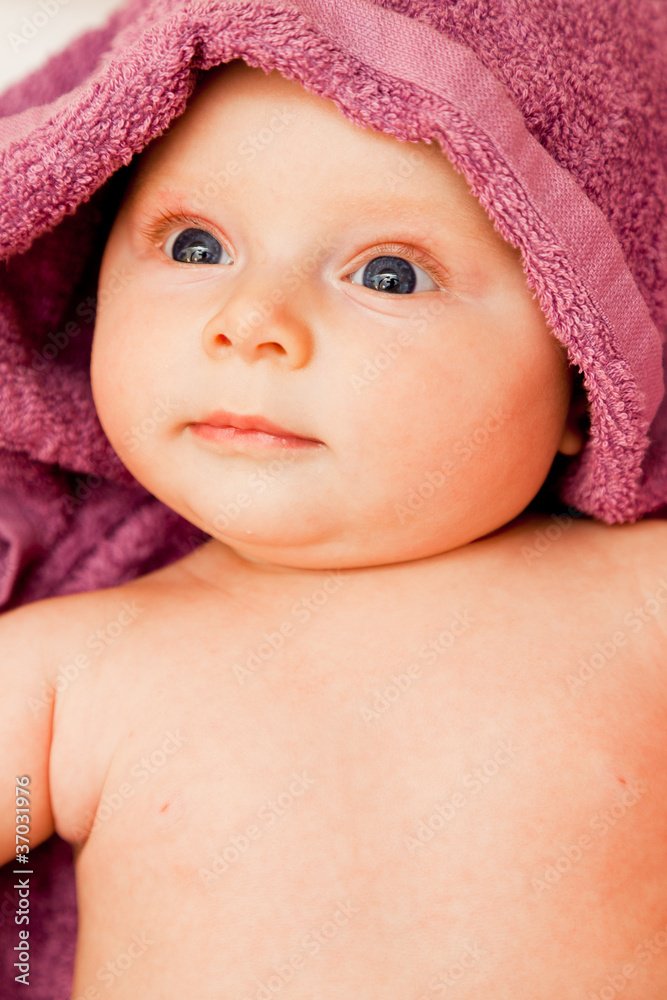 Infant baby girl smiling laying in violet towel Infant baby girl smiling laying in violet towel