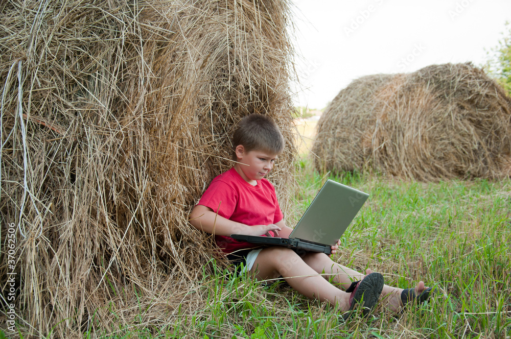 A boy with a laptop in the field A boy with a laptop in the field