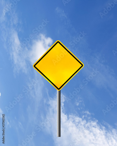 Blank yellow road warning sign on sky