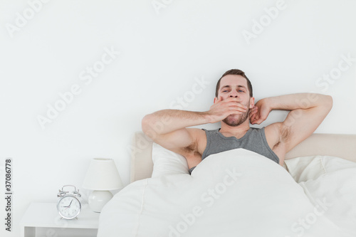 Tired man yawning while waking up
