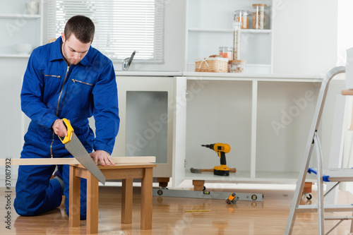 Young handyman cutting a wooden board