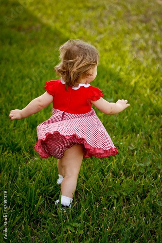 Girl Running Away in Red Dress in Grass