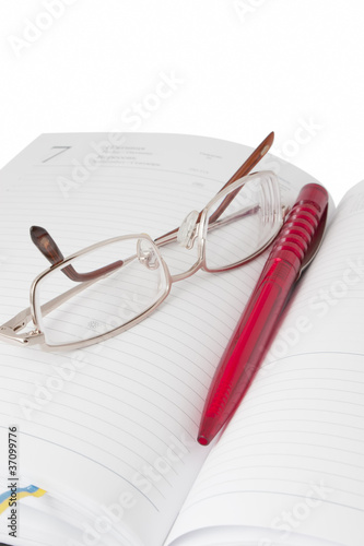 Reading glasses in an open diary with red pen