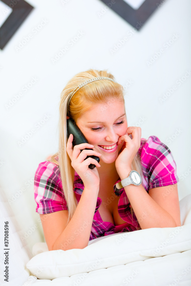 Happy beautiful woman laying on bed and speaking phone Happy beautiful woman laying on bed and speaking phone
