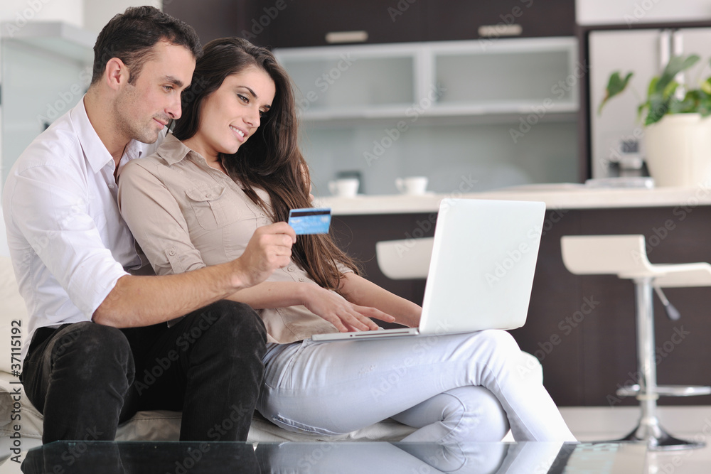 joyful couple relax and work on laptop computer at modern home joyful couple relax and work on laptop computer at modern home