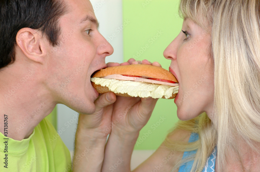 Woman and the man bite a sandwich