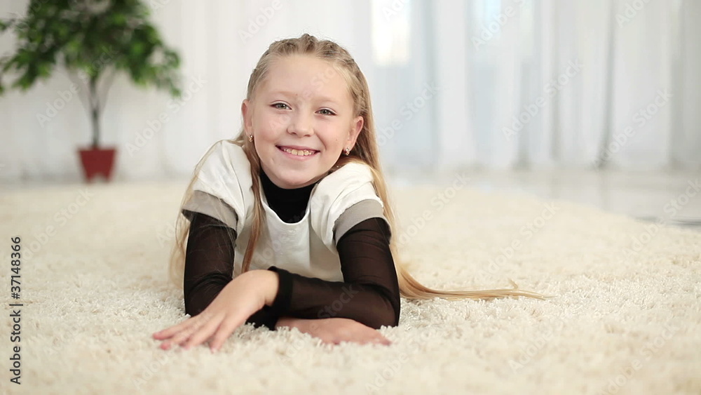 Happy girl lying on the carpet look at camera Happy girl lying on the carpet look at camera