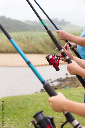 closeup of three people holding fishing rods © michaeljung