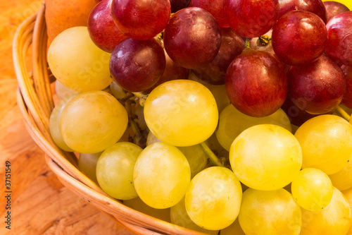 white and red grapes in wickerwork basket