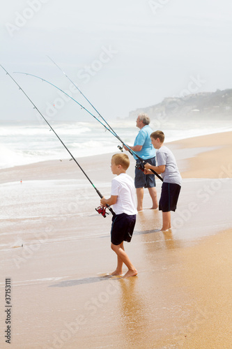 grandfather and two grandsons fishing on beach