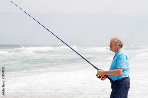 retired senior man fishing on beach alone