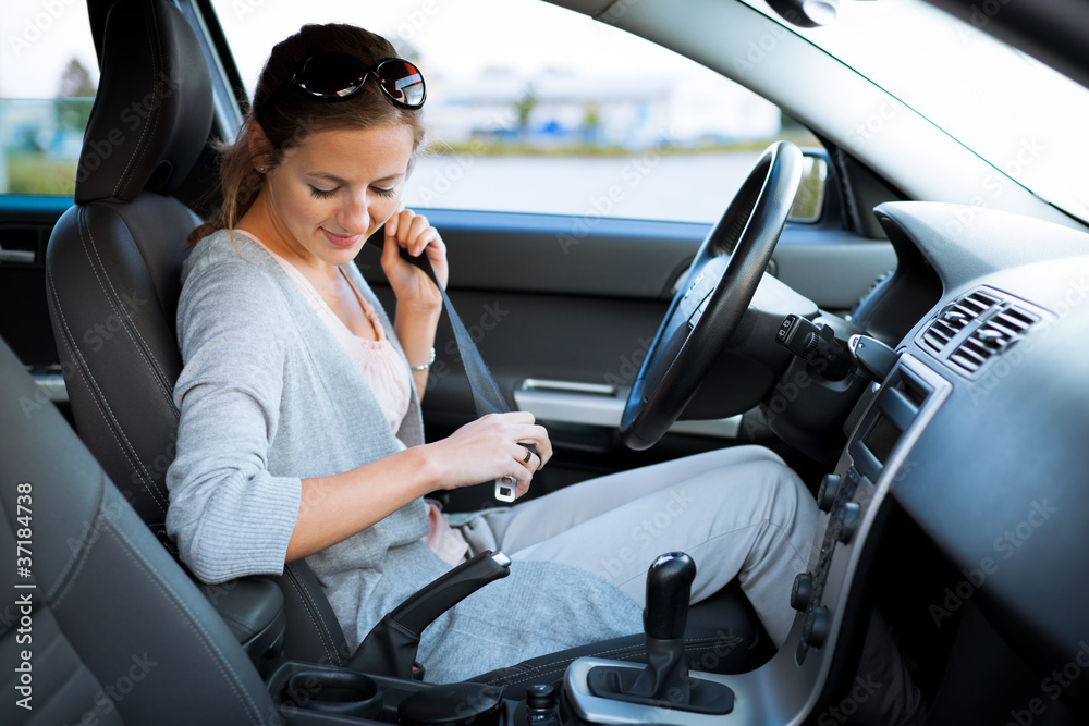 Pretty young woman driving her new car