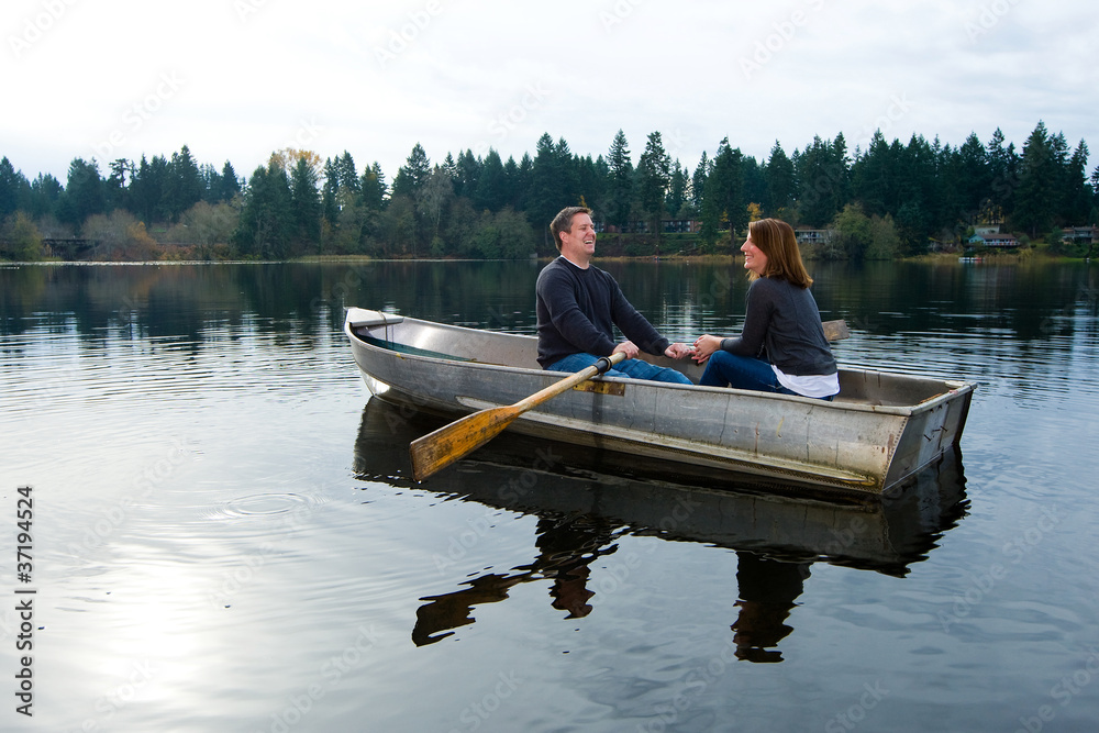 Happy couple in love rowing a small boat on a quiet lake