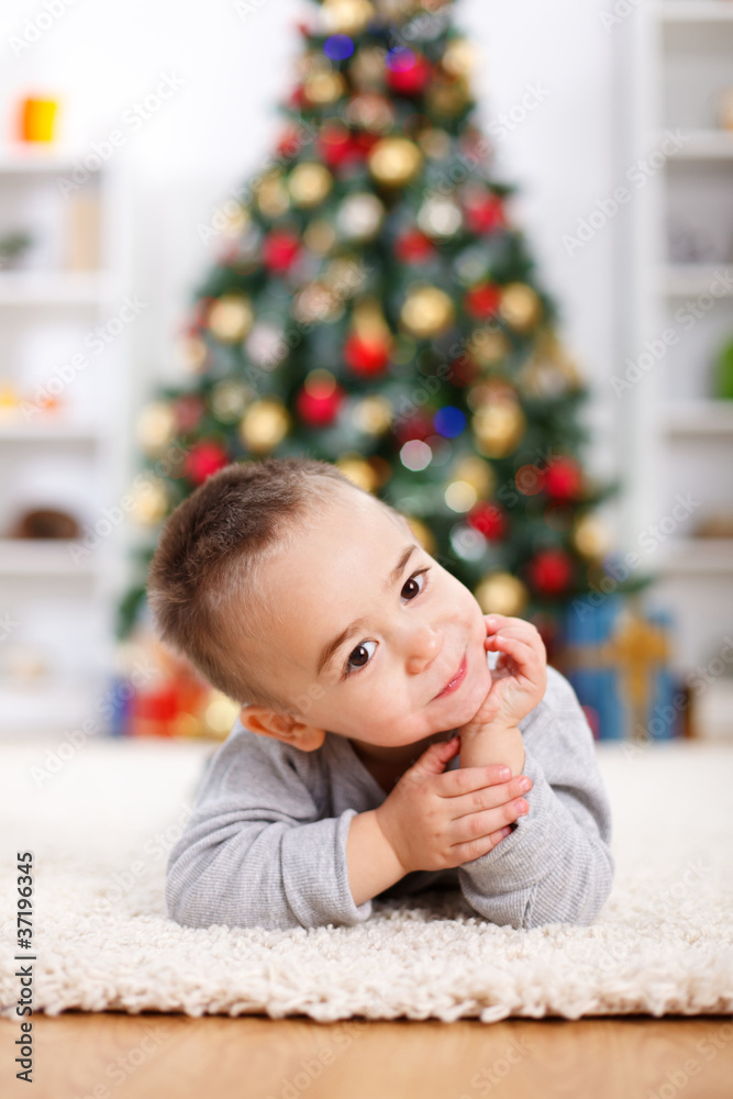 Cute boy laying in front of christmas tree Cute boy laying in front of christmas tree
