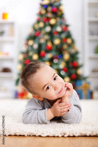 Cute boy laying in front of christmas tree