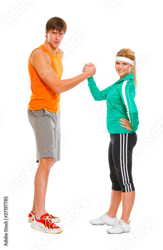 Fit girl and man in sportswear  shaking hands  isolated on white