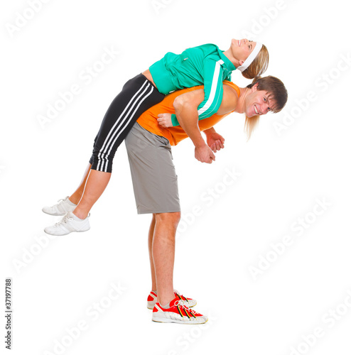 Handsome young man taking slim girl in sportswear on his back