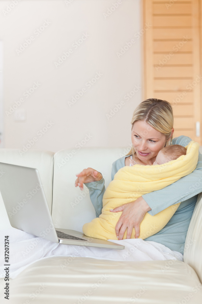 Mother on the couch showing her baby something on the laptop Mother on the couch showing her baby something on the laptop