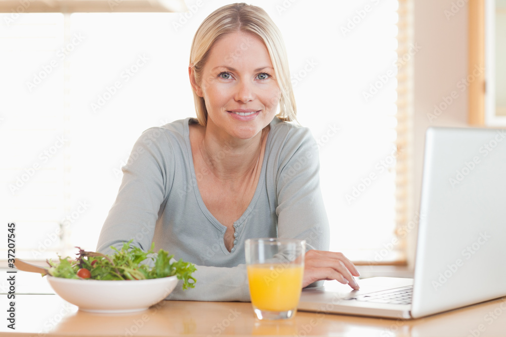 Woman having healthy lunch while working on her notebook Woman having healthy lunch while working on her notebook