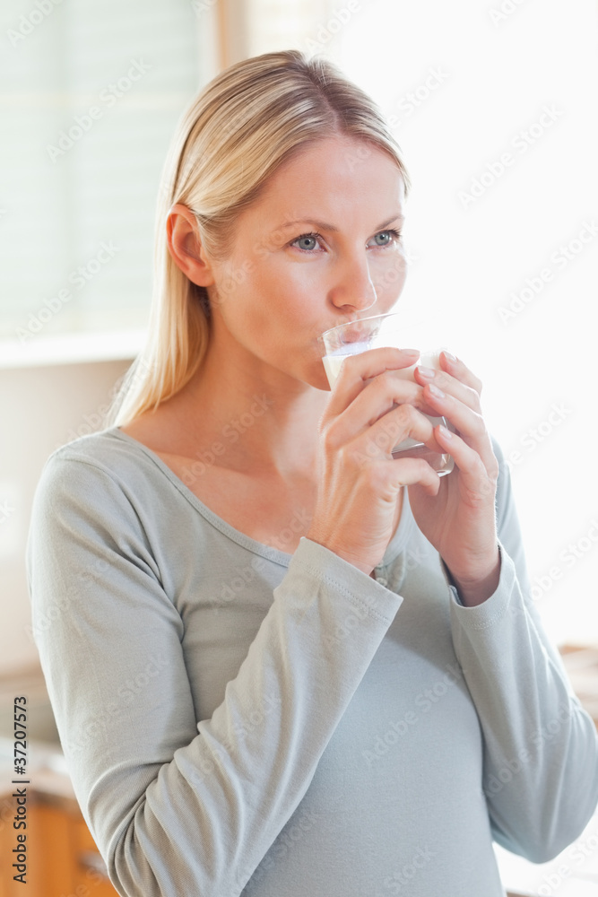 Woman drinking a glass of water in the kitchen Woman drinking a glass of water in the kitchen