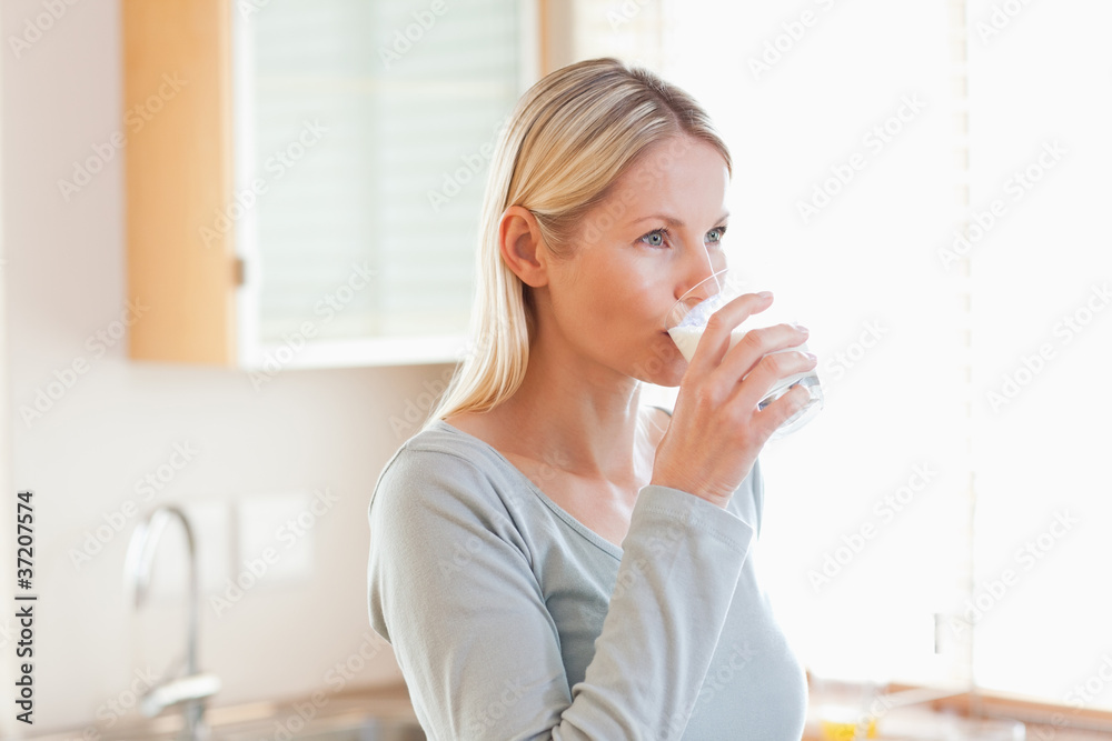 Woman in the kitchen drinking some water Woman in the kitchen drinking some water